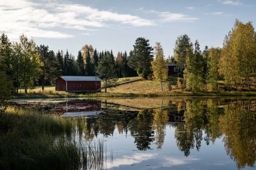 Rauhallinen suomalainen järvimaisema ja metsämökki tyynen veden äärellä