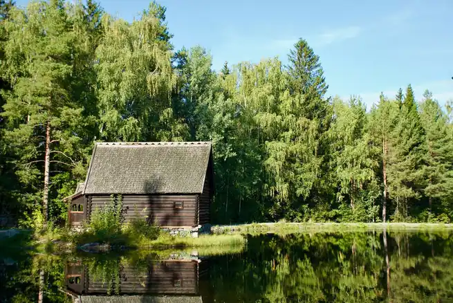 Talvinen lumipeitteinen lomamökki metsän ja järven äärellä